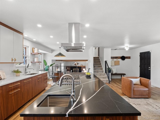 kitchen with a sink, an island with sink, open floor plan, and exhaust hood