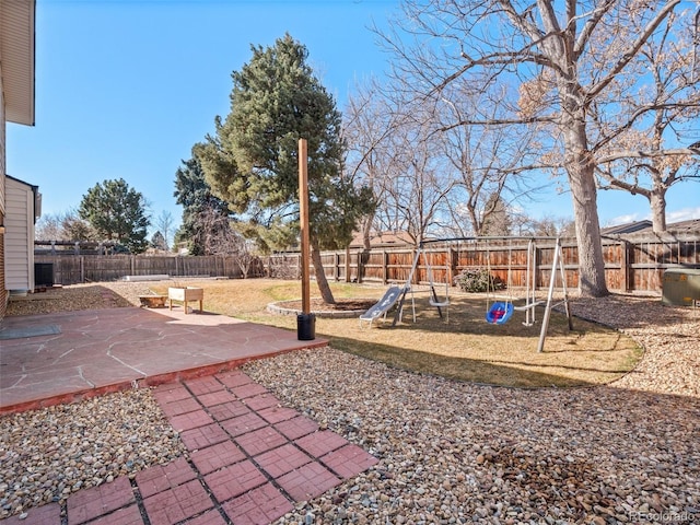 view of yard featuring a patio area, a playground, and a fenced backyard