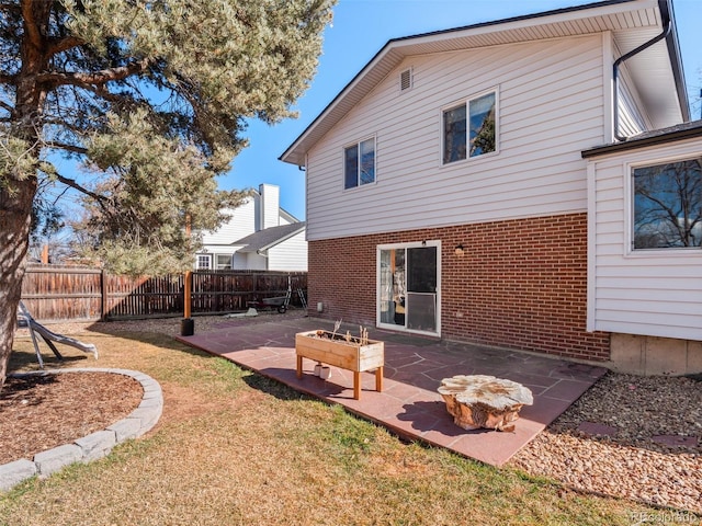 back of property featuring a yard, brick siding, a patio area, and fence