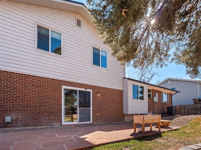 rear view of property with central AC, fence, a patio, and brick siding