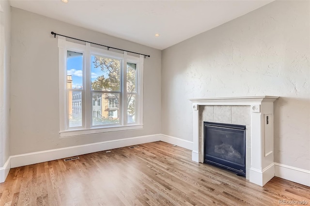 unfurnished living room featuring a tiled fireplace and hardwood / wood-style floors