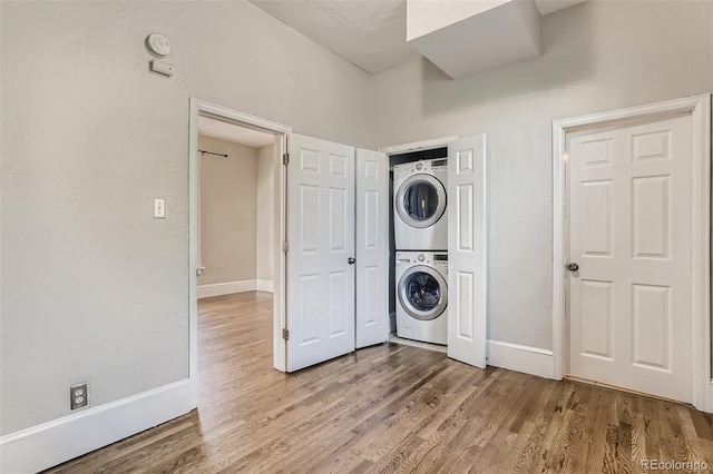 washroom with hardwood / wood-style flooring and stacked washer and clothes dryer