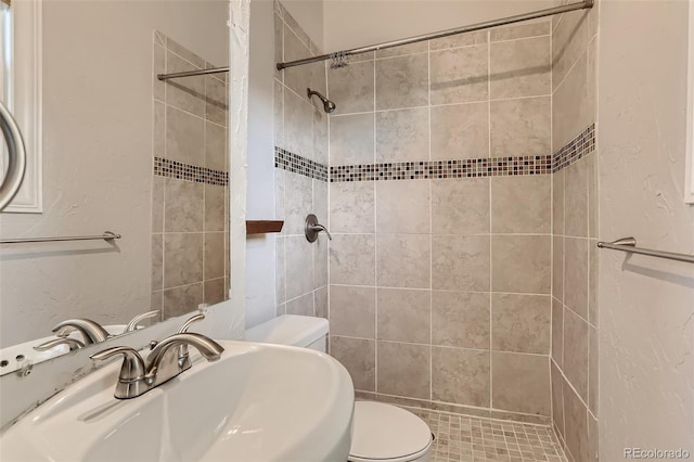 bathroom featuring toilet, sink, and tiled shower