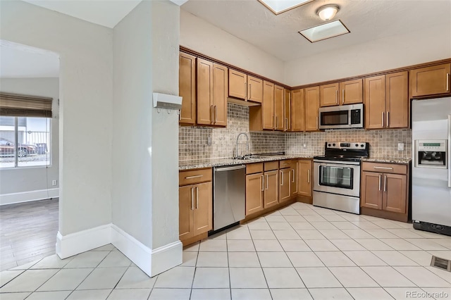 kitchen with light stone counters, sink, tasteful backsplash, and appliances with stainless steel finishes