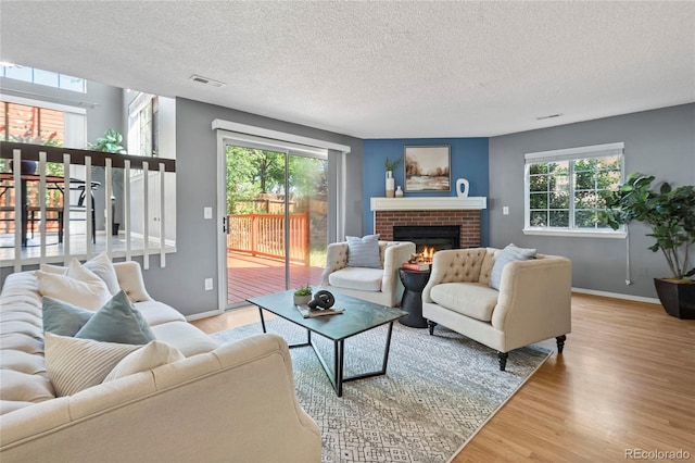 19937 E Loyola Pl, Aurora, CO 80013 - living room featuring light wood-type flooring, healthy amount of natural light, a textured ceiling, and a brick fireplace