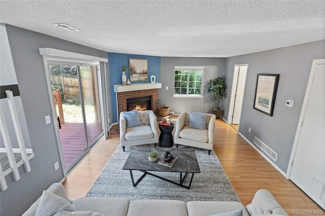 19937 E Loyola Pl, Aurora, CO 80013 - living room featuring light wood-type flooring, a textured ceiling, and a brick fireplace