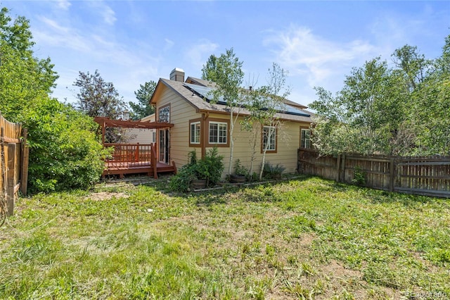 19937 E Loyola Pl, Aurora, CO 80013 - rear view of property featuring a wooden deck, a fenced backyard, solar panels, and a chimney