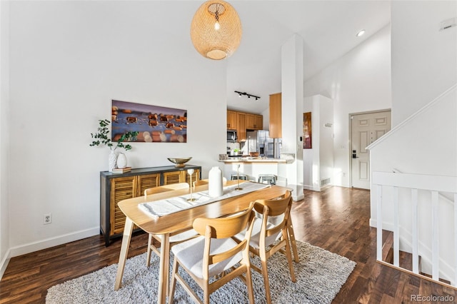 dining room with high vaulted ceiling, track lighting, baseboards, and wood finished floors