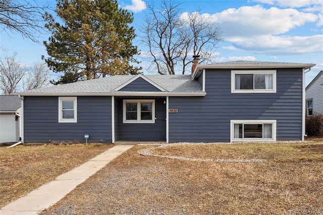 split level home with a chimney and roof with shingles