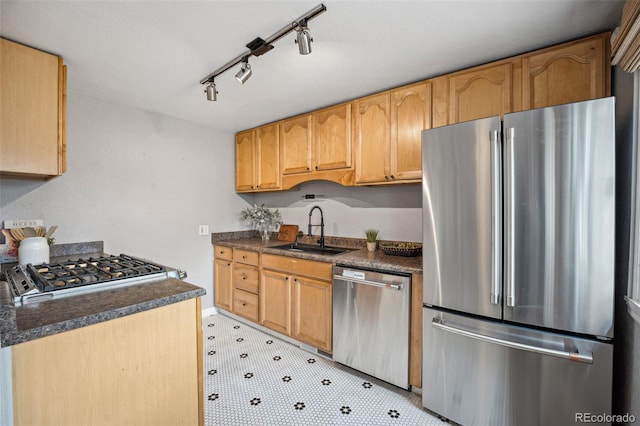 kitchen featuring dark countertops, light floors, appliances with stainless steel finishes, and a sink