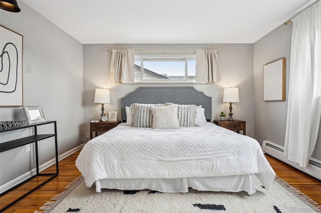 bedroom with baseboards, baseboard heating, and wood finished floors