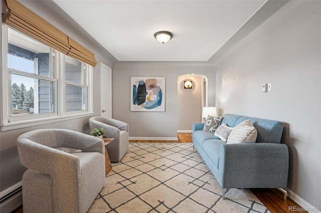 living area featuring light wood-style floors, a baseboard radiator, and baseboards