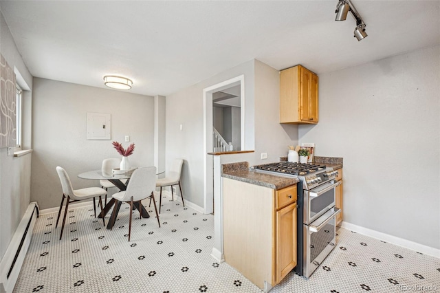 kitchen featuring a baseboard radiator, rail lighting, light brown cabinetry, double oven range, and baseboards