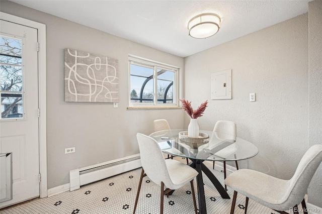 dining room featuring electric panel, baseboards, baseboard heating, and a textured wall