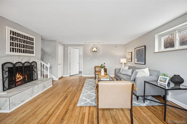 living room featuring visible vents, a fireplace, light wood-style flooring, and baseboards