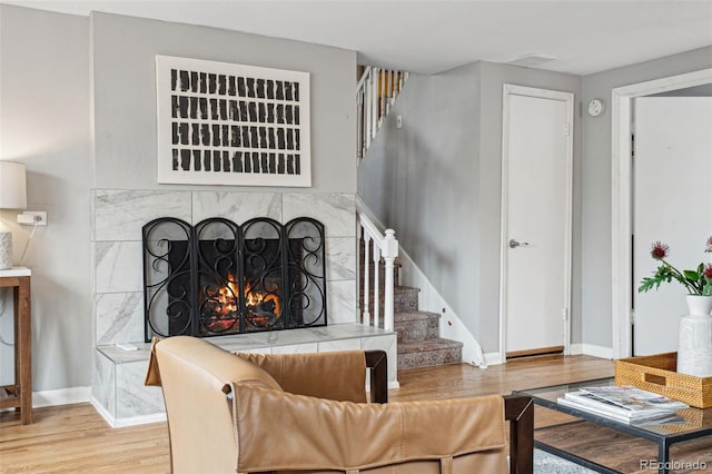 living area featuring baseboards, a fireplace, stairway, and wood finished floors