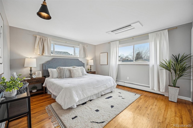 bedroom with a baseboard heating unit and wood finished floors