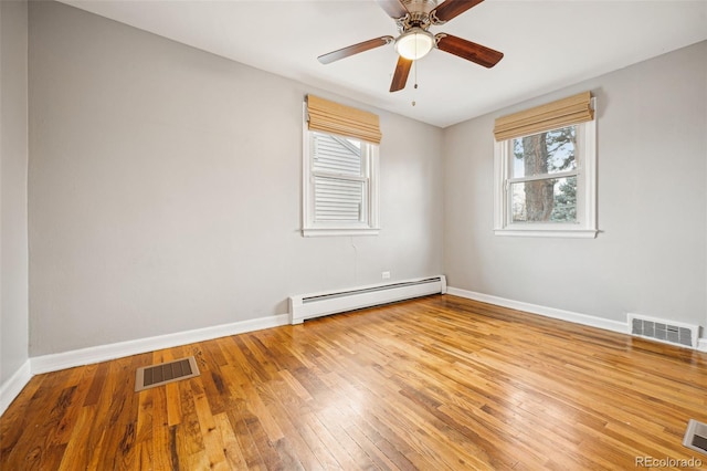 unfurnished room with hardwood / wood-style flooring, a baseboard radiator, visible vents, and baseboards