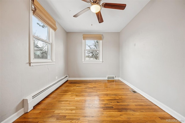 unfurnished room with light wood-type flooring, a baseboard radiator, visible vents, and baseboards