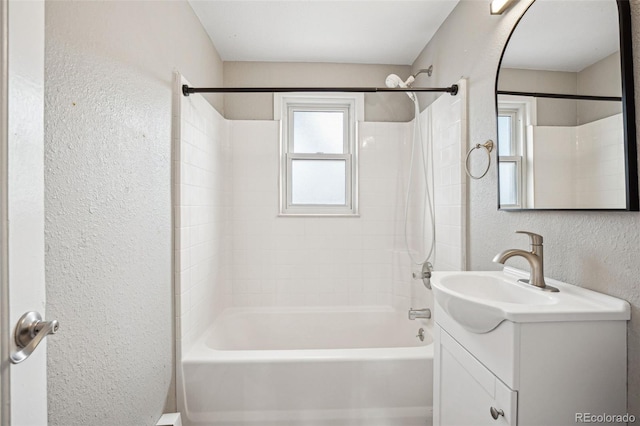 bathroom with bathing tub / shower combination, vanity, and a textured wall