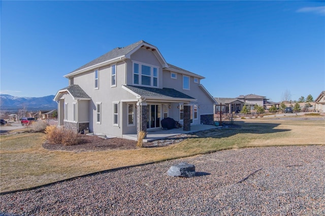 back of house with a patio area, a mountain view, and a yard