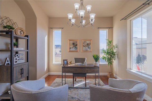 home office with an inviting chandelier and light hardwood / wood-style flooring