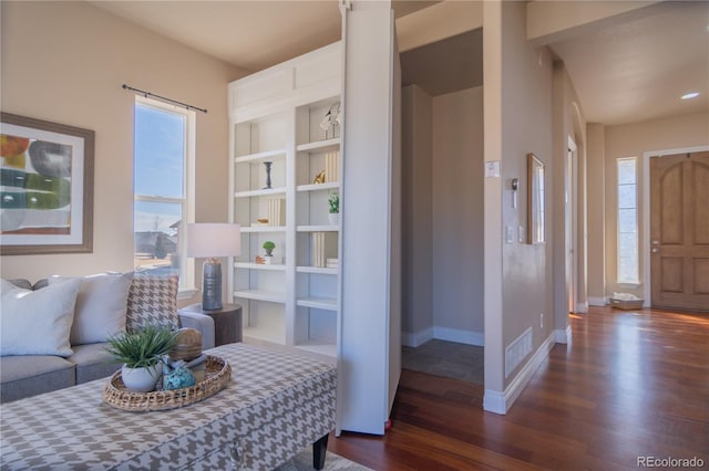 sitting room with built in shelves and dark hardwood / wood-style floors