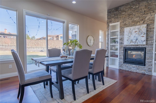 dining area with hardwood / wood-style floors, built in features, and a fireplace