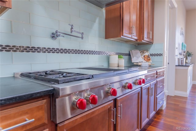 kitchen featuring stainless steel gas stovetop, backsplash, and dark wood-type flooring