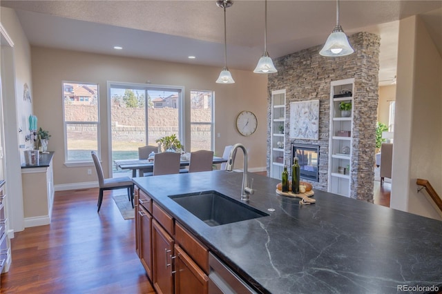 kitchen with sink, hanging light fixtures, dark hardwood / wood-style flooring, built in features, and a fireplace