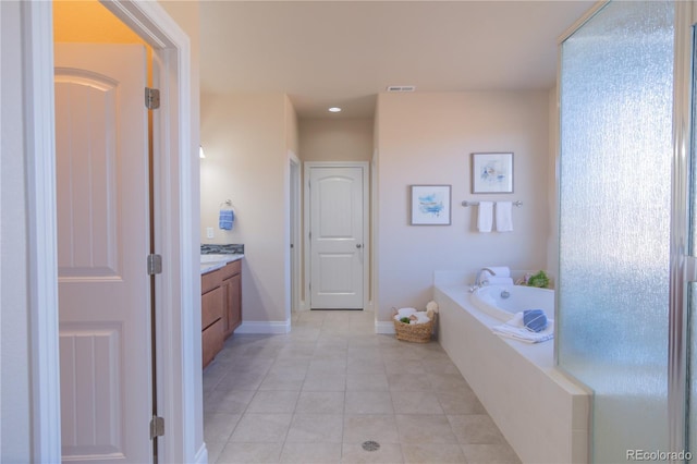 bathroom with tile patterned flooring, vanity, and a bath