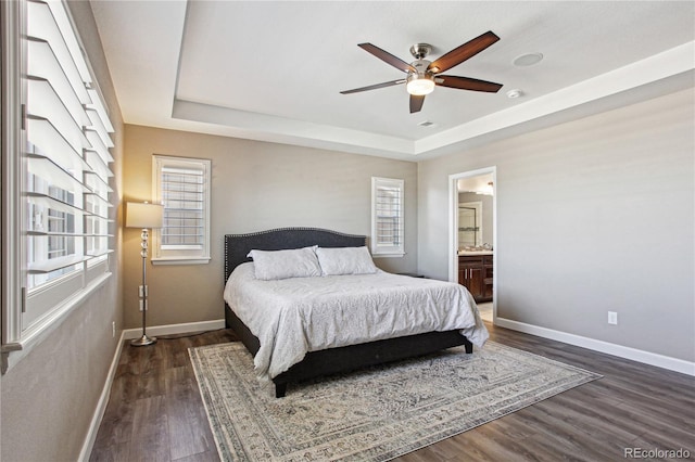 bedroom featuring dark wood-style floors, baseboards, and a raised ceiling