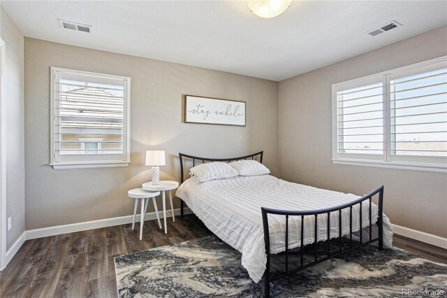 bedroom with baseboards, visible vents, and wood finished floors