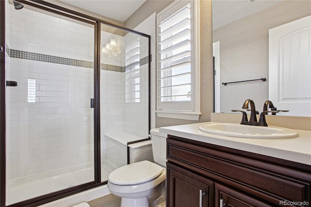 bathroom with vanity, a shower stall, and toilet