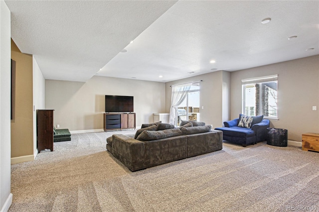 living room featuring a textured ceiling, carpet flooring, a wealth of natural light, and baseboards