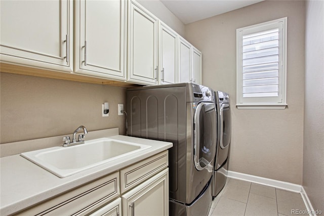 laundry area featuring cabinet space, light tile patterned floors, baseboards, washer and dryer, and a sink