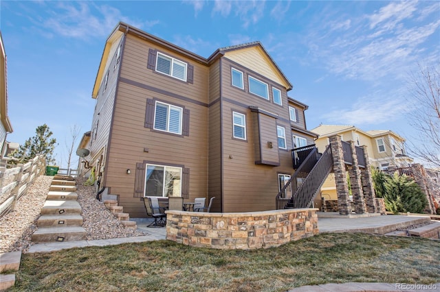 back of property featuring a patio, stairway, and a lawn