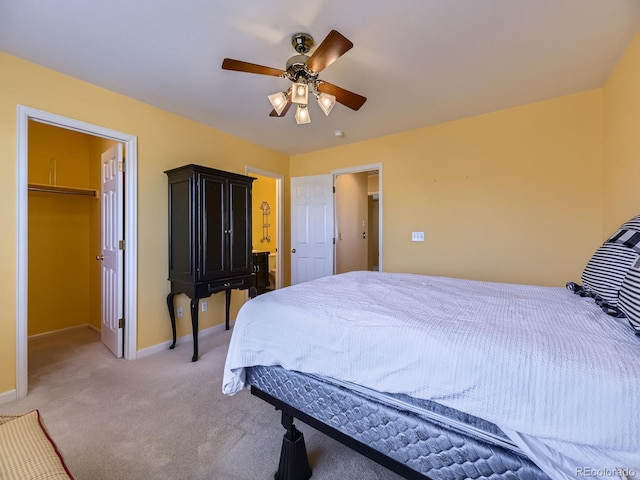 bedroom featuring light carpet, baseboards, a ceiling fan, a spacious closet, and a closet