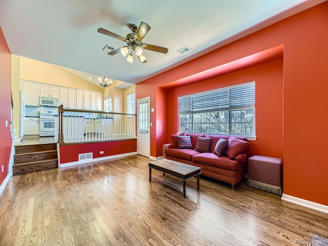 living room featuring lofted ceiling, visible vents, and wood finished floors