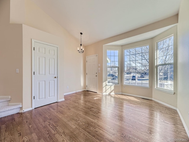 foyer entrance featuring visible vents, lofted ceiling, stairway, wood finished floors, and a notable chandelier