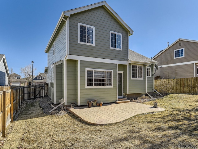 back of property with entry steps, a fenced backyard, and a patio