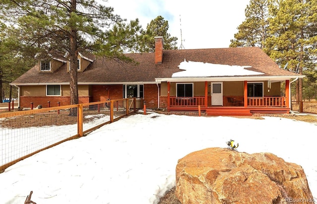 snow covered back of property with a porch