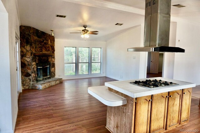 kitchen with tile counters, wood-type flooring, stainless steel gas stovetop, ceiling fan, and island exhaust hood