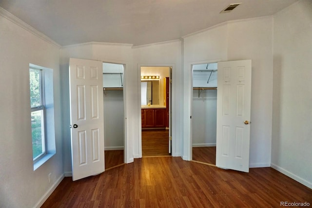 unfurnished bedroom with lofted ceiling, crown molding, connected bathroom, and dark wood-type flooring