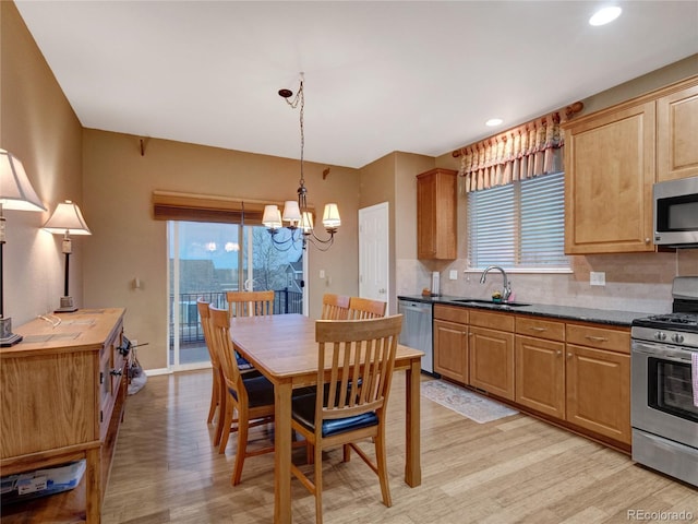 kitchen featuring sink, appliances with stainless steel finishes, tasteful backsplash, light hardwood / wood-style floors, and decorative light fixtures