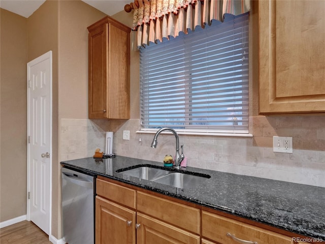 kitchen featuring tasteful backsplash, dishwasher, wood-type flooring, sink, and dark stone counters