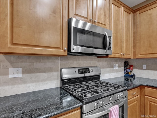 kitchen with dark stone countertops, tasteful backsplash, and stainless steel appliances