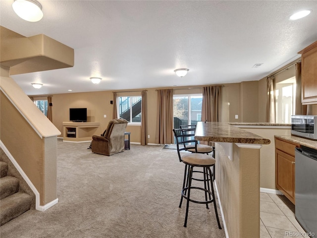 kitchen featuring stainless steel appliances, a kitchen island, light carpet, and a kitchen bar