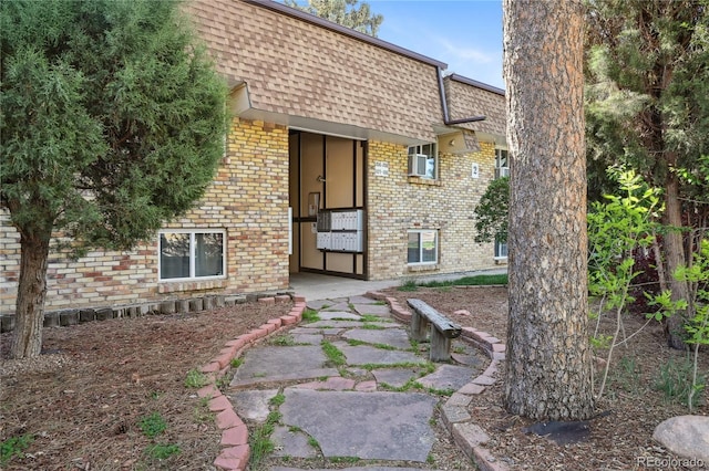 1390 Everett Ct Unit 105, Lakewood, CO 80215 - view of exterior entry featuring mansard roof, brick siding, and roof with shingles
