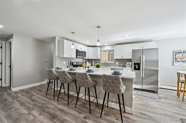1390 Everett Ct Unit 105, Lakewood, CO 80215 - kitchen featuring appliances with stainless steel finishes, a sink, a breakfast bar area, a peninsula, and light countertops